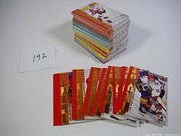 Stacked and fanned hockey rookie cards showing colorful player images and foil rookie designation with red and gold colors.
