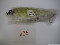 Photo of the bubble-wrapped Motion Buster Jerk Bait fishing lure with a handwritten lot number 235 visible.