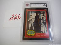 Front view of the graded 1977 OPC Star Wars trading card (#117) featuring Chewbacca posing as a prisoner inside a clear plastic protective case with a grade of 6 ENM.