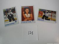 Photo of three hockey trading cards including two goalie cards and a portrait card of a woman