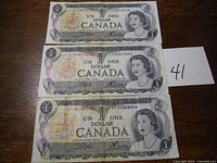 Front side of three 1973 Canadian one dollar bills featuring Queen Elizabeth II and serial numbers.