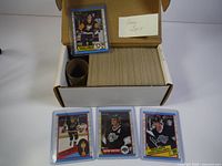 Box containing the full set of hockey cards with cards in protective sleeves visible, with some example cards shown.