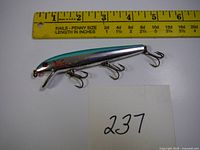 Silver Rattlin Redfin lure with four treble hooks next to ruler showing approx. 5.5 inch length