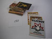 Photo of stack of vintage Playboy collector cards and Playboy magazine cover prints.