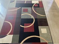 Photo of the full area rug laid out flat on a tiled floor showing its pattern and colors.