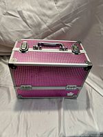 Closed pink hard case with metal trim, handle, and two latches on top