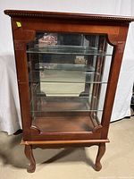 Front view of the wooden glass display case showing three glass shelves and wooden legs.