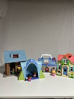 Four Fisher Price Little People play-sets with six Little People figures displayed on white surface.