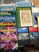 Photo of gardening and bird related books including 'How to Grow Roses', 'Pruning Handbook', 'Gardens!' magazines, 'Right Plant, Right Place', 'Garden Encyclopedia', and bird related guides such as 'The Audubon Master Guide to Birding'.