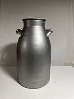 Front view of silver spray painted milk can showing cylindrical shape and side handles