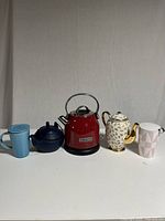 Full front view of all items in the lot with kettle center, tea pots, and mugs