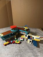 Photo of the full set including airport terminal, airplane, helicopter, and multiple Little People figures with various vehicles on a gray surface.
