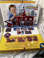 Box back showing the Imaginext Rescue Center with fire station, fire truck, ladder, satellite dish, and child playing with set.