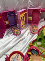 Photo of pink fold-out Polly Pocket compact cases open showing interior play surfaces and miniature furniture.