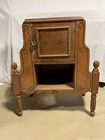 Front view of vintage wooden cabinet with carved sides and turned legs.