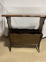 Full side view of wooden hall table showing flat tabletop surface and magazine rack below with scalloped edges and curved legs.
