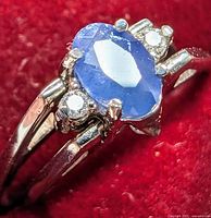 Close-up of oval blue sapphire and diamond accents on one side of the ring