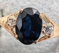 Close-up of oval deep blue sapphire and single lab diamond on one side of ring
