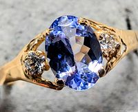 Close-up of ring showing oval tanzanite center and two diamond side stones