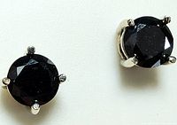 Front view of pair of stud earrings showing round faceted black diamonds and prong settings