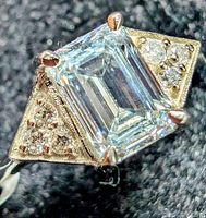 Top-angled close view of emerald-cut center stone and side clusters