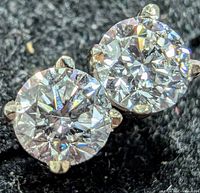 Close-up front view of both round brilliant diamonds in white gold prong settings on black background, showing brilliance and clarity.