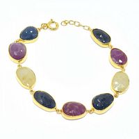 Close-up image of the gold plated silver bracelet showing the faceted sapphire, ruby, and emerald stones in bezel settings.
