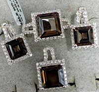Close-up view of the smokey quartz ring, earrings, and pendant on a gray display surface