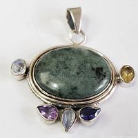 Front view of silver pendant with green central oval stone, and surrounding stones including citrine and amethyst.