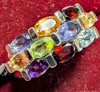 Close-up image showing the multi gemstone silver ring front with visible purple, green, blue, yellow, and red stones