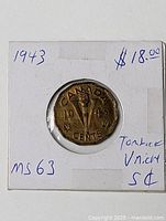 Coin in 2x2 holder, reverse side showing torch and V design