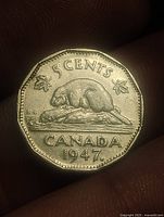 Reverse of 1947 Canadian 5 cent coin showing beaver, maple leaves and date.
