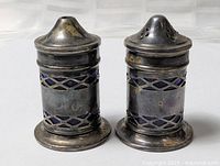 Front view of both salt and pepper shakers showing silver-plated bodies and blue glass liners