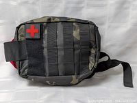 Front view of closed camouflage first-aid pouch with red cross patch