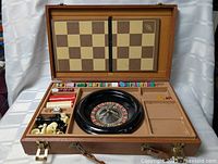 Open case showing roulette wheel, chips, chess pieces, board