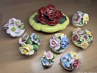 Photo showing all porcelain floral bouquets and the yellow covered dish with large red rose on top arranged on a wooden surface