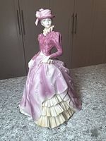 Porcelain figurine full view on counter, Victorian-style woman in elegant dress and hat