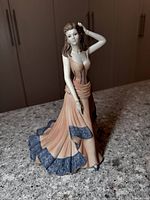 Front view of the Coalport porcelain figurine showing detailed peach-colored gown with blue ruffle accents and the figure's pose.