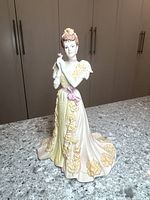 Full view of the figurine showing the color scheme, dress details, and overall size standing on a countertop.