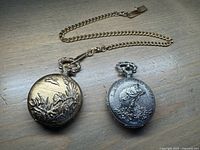 Both pocket watches shown closed from front with animal and nature themed designs on covers