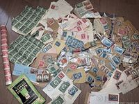 Overview of many loose Canadian postage stamps, envelopes with stamps, and multiple sheets, displayed spread out on a flat surface.