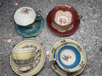 Four cups and saucers displayed with intricate floral and gold designs