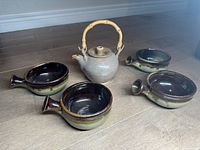Photo of the teapot and four soup bowls arranged on the floor, showing the set composition and bamboo handle on teapot.