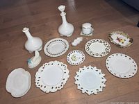 Full assortment of Victorian milk glass items on floor including plates, decanters, hen in basket figurine, and small decorative dishes.