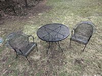 Three-piece set outdoors on grass, two chairs flanking round mesh table