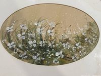 Close-up of one watercolour painting depicting white flowers and greenery on a muted beige background, oval framed