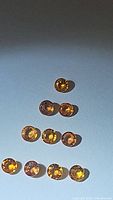 Photo of 10 round cut vivid fanta orange sapphires, arranged in a pyramid shape showing color and clarity.