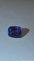 Close-up of cushion cut natural tanzanite showing deep blue and purple color with visible facets.