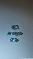 Four oval cut blue zircon gemstones placed on a white background under natural light showing clarity and color.