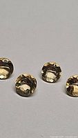 Close-up photo of four round cut golden citrine gemstones arranged on a flat surface showing their size, clarity and color.